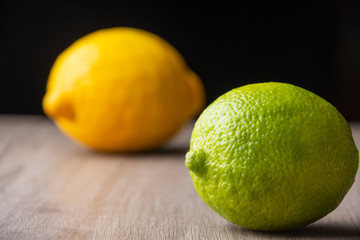 Close-up of a lime and a lemon, on a table on a black background, with selective focus, horizontal