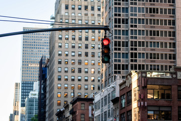 Traffic light with red light above Manhatan street among many skyscrapers