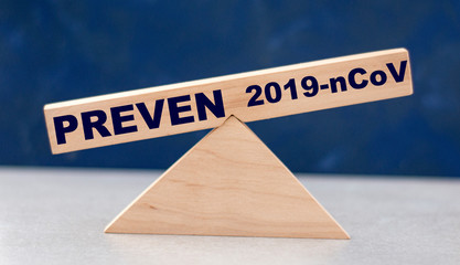 the concept of the balance of stop words and the 2019-nCoV on wooden scales on a blue background