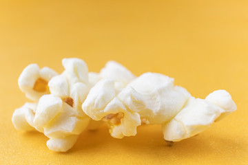 Close-up popcorn on a bright yellow background, macro photo. The concept of unhealthy delicious food, entertainment, a snack in the cinema. Copyspace.