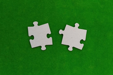 Two pieces of cardboard puzzles on a green background. the details of the interaction.