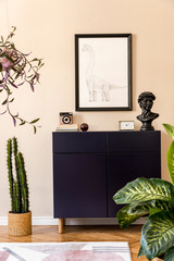 Modern composition of home staging with navy blue commode, plants, cacti, mock up poster frame, design carpet and elegant personal accessories. Beige walls. Stylish living room. Home decor. Template. 