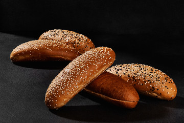 Variety of fresh baked bread with black and white sesame seeds against dark background with copy space. Rural cuisine or bakery. Close-up