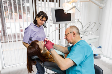 Senior male dentist doctor and his female nurse treats a patient. Dentistry and healthcare, oral care concept