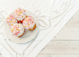 Happy Easter cake with sprinkles on glaze. Cake on light green rustic board, lace cloth, blur green plants and sun. Homemade bakery, spring holiday preparation. Selective focus, free text space.