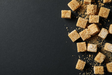 Brown sugar cubes on black background, top view