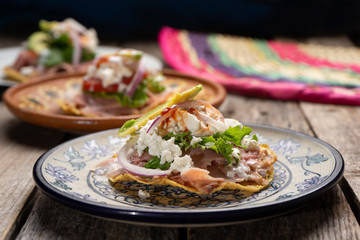 Mexican ham toast also called tostadas with beans and cheese on wooden background
