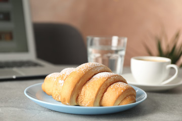 Composition with croissant and computer on grey table, close up