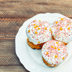 Happy Easter cake with sprinkles on white glaze. Easter cake on old rustic wooden board, lace cloth. Festive homemade bakery, spring holiday preparation. Selective focus, free text space.