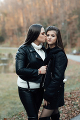 Two girls young model walk. Two pretty cuter teenagers shares. Best friends wearing stylish outfit, autumn outdoor.