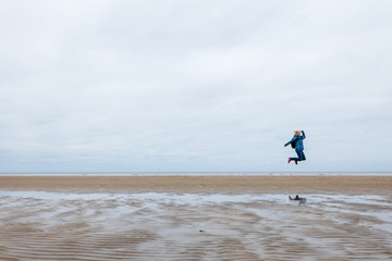 girl jumping on the background of the sea in a cold season