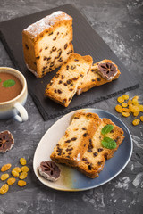 Homemade cake with raisins, dried persimmon and a cup of hot chocolate on a black concrete background. Side view, copy space.