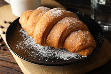 Composition with delicious croissant on wooden background, close up