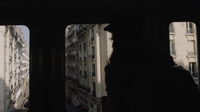 Silhouette of happy beautiful tourist woman riding Paris metro train, watching city buildings through window slow motion