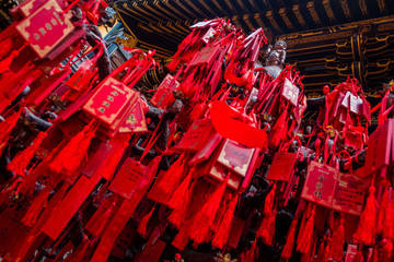 Chongqing, China:  Sculpture of a little Buddha onRed tablets and ribbons with mantras, prayers on...