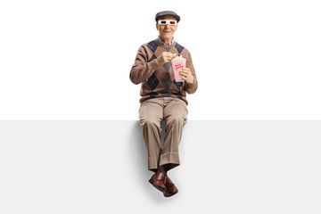Elderly man with 3d glasses sitting on a panel eating popcorn
