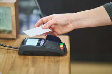 Close up hand paying order by credit card on payment terminal in the coffee shop