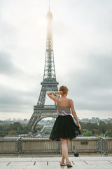 Girl in a black skirt near the Eiffel tower in Paris. Back view