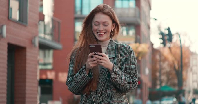 Beautiful Woman walking in the Crowded Street with Mobile Phone in her Hands. Using Internet and social Networks. Looking stylish and Gorgeous. Trandy Outfit. Sunny day. Smiling Woman. Smartphones.