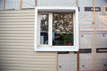 Wall covering of the frame house with panels of vinyl siding of gray color. Decorating the house with siding. The master updates the look of the old house with siding.