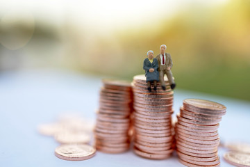 Miniature people: Happy old people sitting on coins stack, Retirement  and Life insurance Concept.