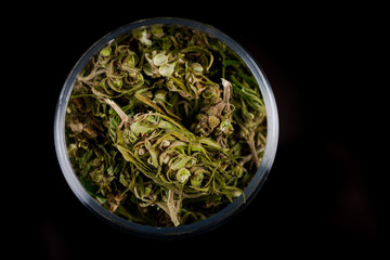 Cannabis Flower Buds in Glass Jar, Top Down Close Up. Dark Background. Medical Marijuana Concept