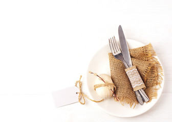 Easter background. Table setting for the holiday of Easter in a rustic style,burlap napkin, wooden egg, fork and knife on a white plate. Copy space, top view