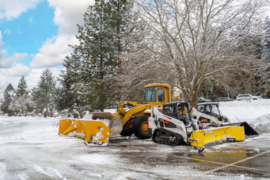 Snow removal vehicles sit idle in a parking lot of a suburban American City after a winter storm.