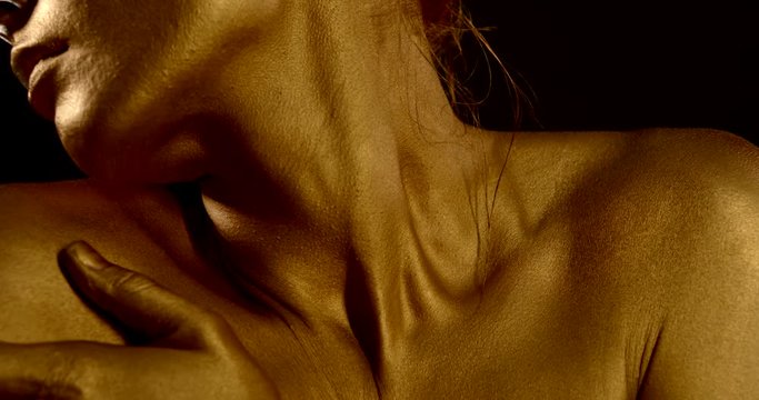 sensual excited woman is rubbing golden dye on skin of neck and shoulders, detail view