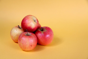 a pile of red apples isolated on yellow background flat lay