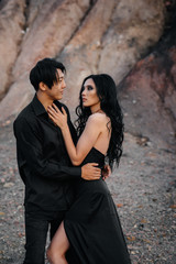An Asian couple in love in black leather clothes walk in nature among the trees. Style, fashion, love