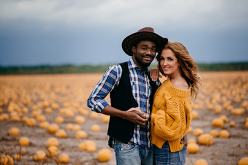 Portrait of a happy young couple of farmers on the background of a pumpkin crop.