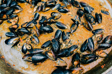 delicious oysters cooked in a large frying pan in a creamy tomato sauce at a street market