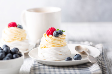 Delicious Pavlova cake with whipped cream and fresh berries. White cup of coffee. Selective focus