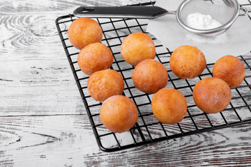 Golden round donuts on the black lattice on the white wooden table