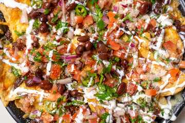Mexican nachos with beans and pico de gallo sauce on white background