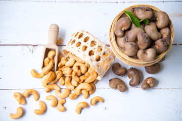 Roasted salted raw cashew nuts with Fresh cashew in spoon and  basket isolated on white wooden...