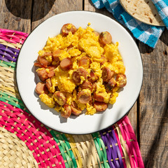 Scrambled eggs with sausage breakfast on wooden background