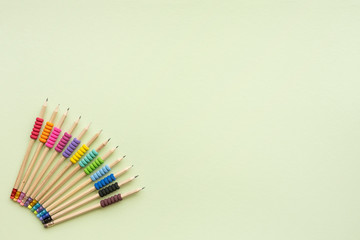 Variety of eco friendly wooden pencils with colorful grip  on green background with copy space