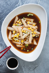 Grey bowl with korean black soybean sauce topokki, flatlay over grey concrete background, studio shot