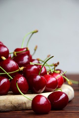 Rote Kirschen frisch geerntet auf einem Holzbrett und einem Holztisch, isoliert und freigestellt