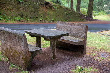 Recreation area on the highway in the forest. A table and benches made of stone are shown in close-up. Concept: in harmony with nature.