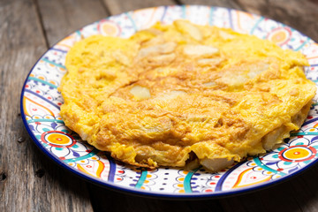 Spanish scrambled eggs with potatoes called tortilla or tapa on wooden background