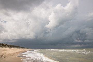 plage vide avec une personne sous un ciel d'orage