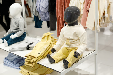 black sitting baby mannequin without face in a shop window of a children's clothing store.