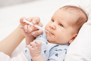 Mother feeding newborn baby with liquid Vitamin K
