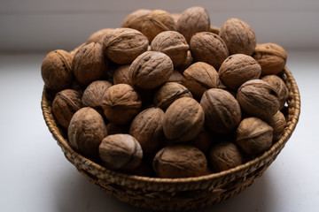 Small wicker basket filled with walnuts on a white background