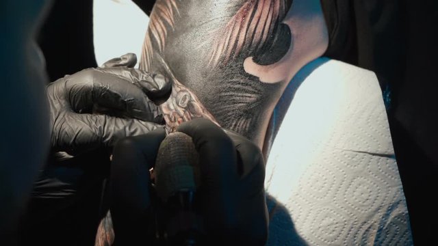 Close up video of doing black tattoo of snake on woman in studio