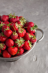 Fresh juicy strawberries from the garden in an iron bowl on the table. Heap of fresh strawberries in an iron bowl on rustic white wooden background. Fresh organic berries macro. Free space for text.