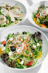 mixed fresh organic salads on white restaurant table